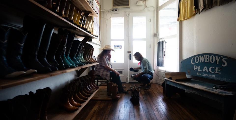 Full Circle Vintage Owner and boot-finder Joey Medina, right, fits Jan Bessette for a new pair of boots in his Lockhart store, June 30, 2023. Medina travels across Texas and the United States collecting vintage cowboy boots to repair and resell, giving them a second life and preserving Texas history. "I love finding someone their perfect pair of boots," said Medina. "And I really get excited when someone comes through the door and they think we won't have what they're looking for... and we happen to have it."