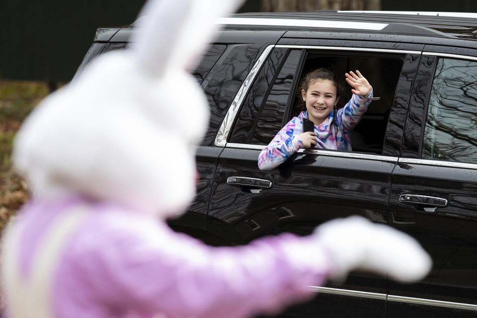 A girl waves to the Easter Bunny from her family's car as they travel past the Waverly Community House in Waverly Twp., Pa., Saturday, April 4, 2020. With the Waverly Community House's annual Breakfast with the Bunny event cancelled due to the COVID-19 outbreak, children were given the opportunity to wave to the Easter Bunny from a safe distance while staying in their cars. (Christopher Dolan/The Times-Tribune via AP)