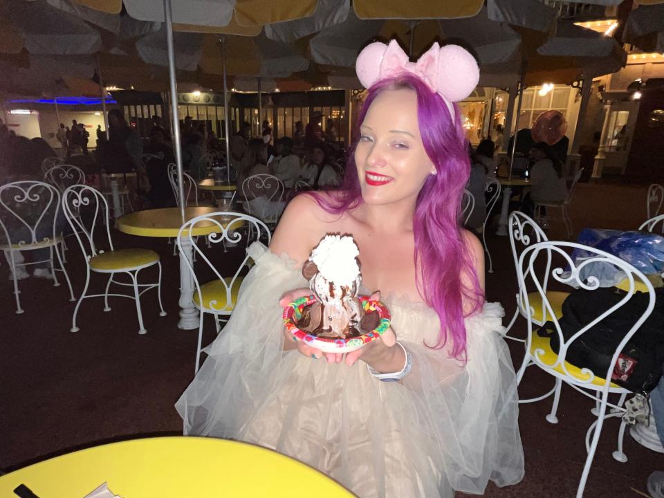 jenna posing with an ice cream sunday at a table outside on main street usa in magic kingdom