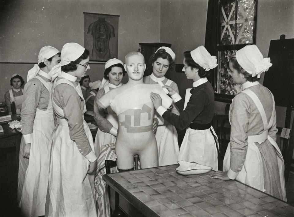 A sister tutor instructing student nurses bandaging the torso of a mannequin, at Atkinson Morley’s Convalescent Hospital, Copse Hill, London