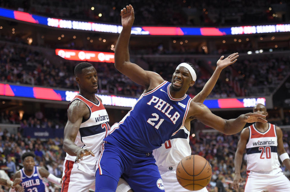 Washington Wizards center Ian Mahinmi, left, fouls Philadelphia 76ers center Joel Embiid (21) during the first half of an NBA basketball game, Wednesday, Oct. 18, 2017, in Washington. (AP Photo/Nick Wass)