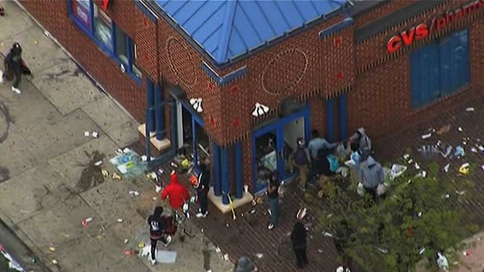 In this frame from video provided by WJLA, people gather near a store Monday, April 27, 2015, during unrest following the funeral of Freddie Gray in Baltimore. Rioters plunged part of Baltimore, torching a pharmacy, setting police cars ablaze and throwing bricks at officers. (WJLA via AP) MANDATORY CREDIT
