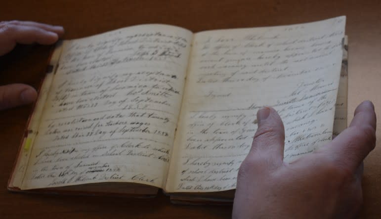 Minutes from a community meeting held in the Town of Pittsfield, Wis., on Nov. 15, 1856 show the vote on the area’s first school, and subsequently the tax to fund it. Howard-Suamico School Superintendent Damian LaCroix keeps the records close at hand to remind him of the area’s historical commitment to funding schools. (Ben Rodgers / Press Times)<br>