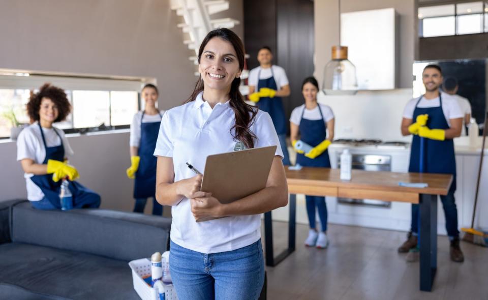 A woman smiles while a team of cleaners pose behind her. 