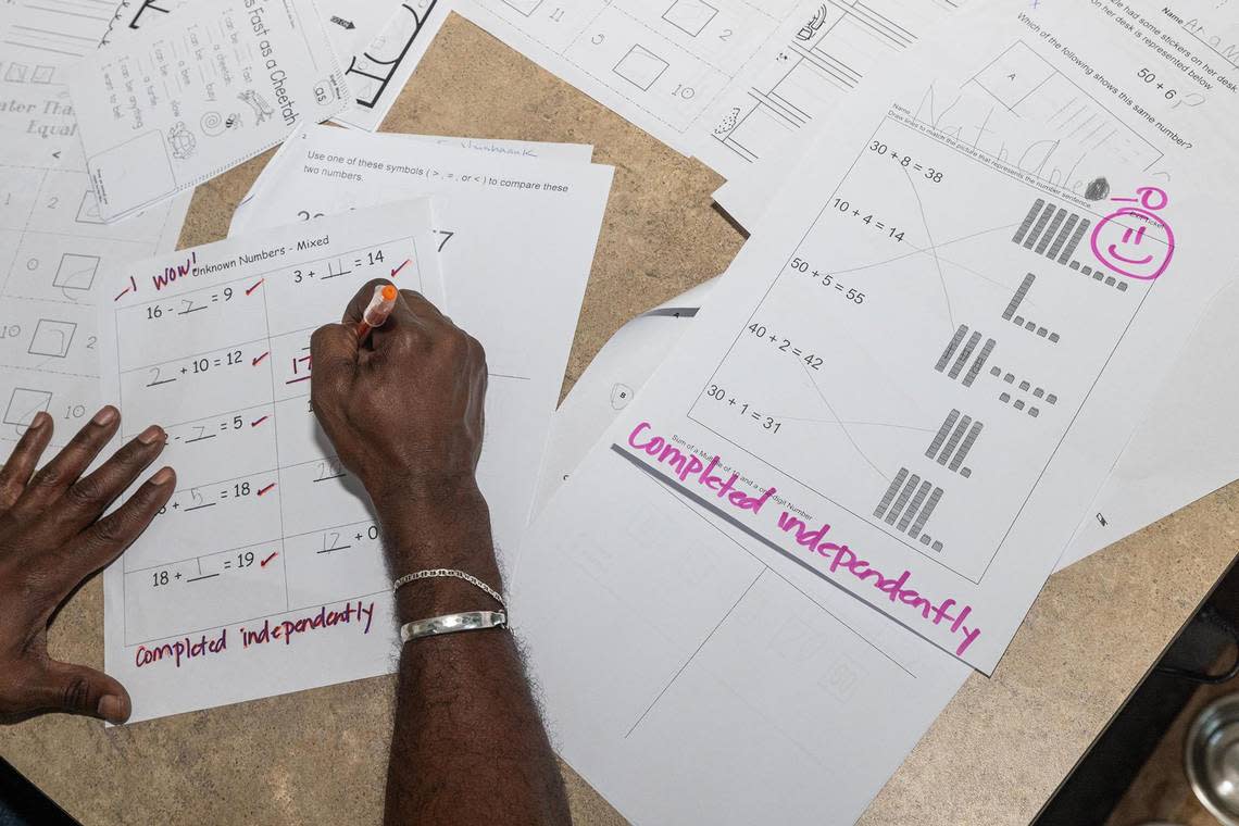 Special Education teacher Quincy Luper grades his students homework assignments at his home in Fort Worth on Wednesday, Dec. 6, 2023. Luper teaches at Willis Lane Elementary School and said he often stays late to finish work and uses his own money to supply his students with what he needs.