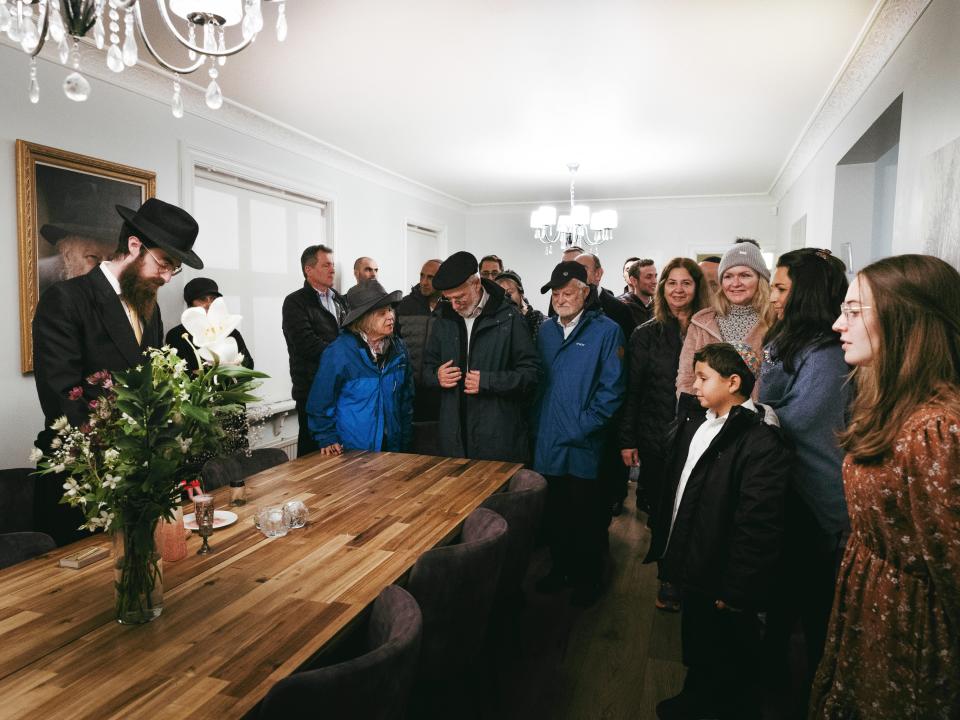 People meeting in a room, with a Rabbi performing a ceremony.