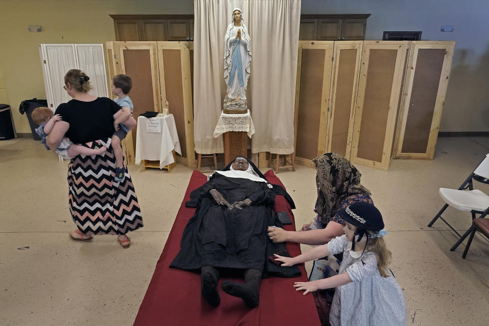 People pray over the body of Sister Wilhelmina Lancaster at the Benedictines of Mary, Queen of Apostles abbey Sunday, May 28, 2023, near Gower, Mo. Hundreds of people visited the small town in Missouri this week to see the nun's body that has barely decomposed since 2019 — some are saying it's a sign of holiness in Catholicism, while others are saying the lack of decomposition may not be as rare as people think. (AP Photo/Charlie Riedel)