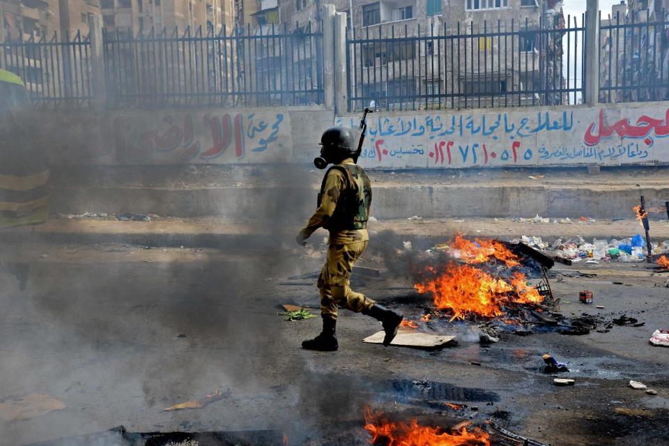 A military soldier walks through heavy smoke from clashes with supporters of Egypt’s ousted Islamist President Mohammed Morsi in Mediterranean city of Alexandria, Egypt, Friday, Jan. 3, 2014. The confrontations spilled from main streets to side streets in heavily populated residential areas in several provinces including Cairo, Giza and Alexandria. Dozens of Muslim Brotherhood members and supporters hurled rocks at security forces, which responded with volleys of tear gas. (AP Photo/Heba Khamis)