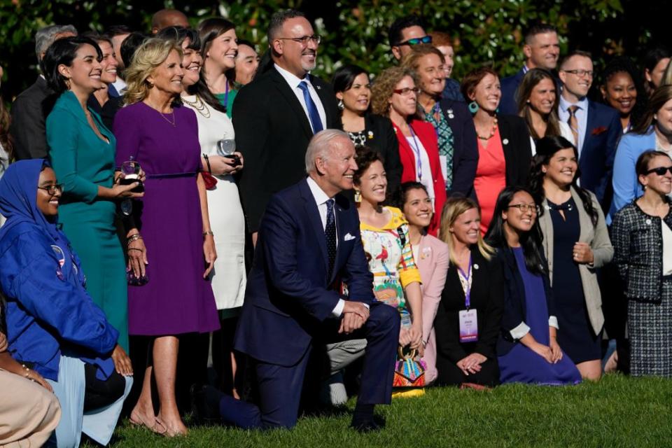 President Joe Biden kneels photo at the end of an event hosted by first lady Jill Biden to honor State and National Teachers of the Year, on the South Lawn of the White House, Monday, Oct. 18, 2021, in Washington. Standing third from left is Juliana Urtubey, 2021 National Teacher of the Year, first lady Jill Biden, Tabatha Rosproy, 2020 National Teacher of the Year and Education Secretary Miguel Cardona. - Credit: AP