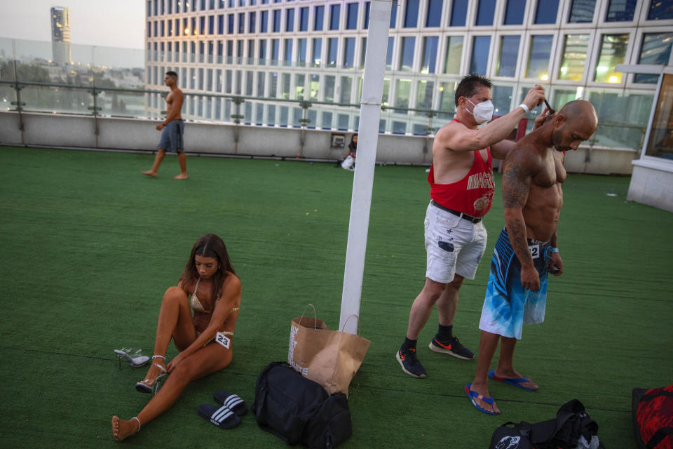 Contestant have his body painted backstage during the National Amateur Body Builders Association competition in Tel Aviv, Israel, Wednesday, Aug. 19, 2020. Because of the coronavirus pandemic, this year's competition was staged outdoors in Tel Aviv. The 85 participants were required to don protective masks in line with health codes. (AP Photo/Oded Balilty)