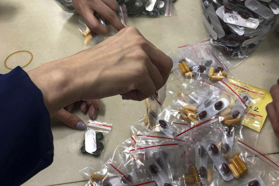 FILE - In this Sunday, Dec. 1, 2019, photo, workers pack multi-colored supplement pills in small resealable bags at an industrial building in Hong Kong. By day, the small commercial kitchen in a Hong Kong industrial building produces snacks. At night, it turns into a secret laboratory assembling a detox kit to help frontline pro-democracy protesters counter ill-effects from repeated exposure to tear gas. (AP Photo)