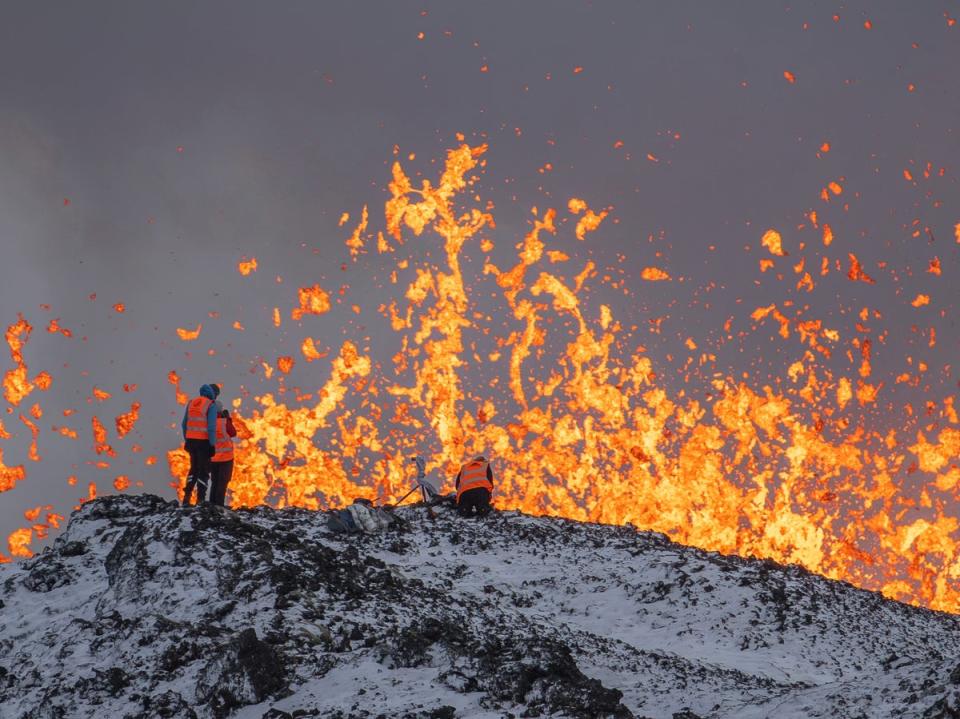 Scientist of the University of Iceland take measurements and samples standing on the ridge in front of the active part of the eruptive fissure of an active volcano in Grindavik (AP)