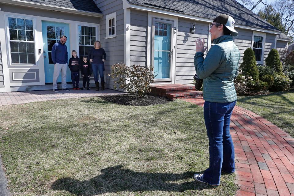 Photographer Jen Bauer arranges the self-isolating Bates family for a portrait on March 27, 2020, as part of the Front Steps Project in North Andover, Mass., to raise money for local charities by offering portraits from a distance.