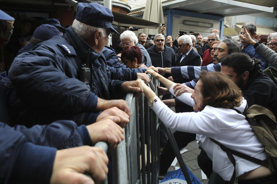 Protesters pull the barriers set up by the police as they demonstrate against the closing of a crossing point straddling a United Nations-controlled buffer zone in divided capital Nicosia, Cyprus, Saturday, Feb. 29, 2020. Around 200 people gathered at the Ledra Street crossing point to voice their opposition to it closing. The Cyprus government said it closed the Ledra Street crossing point along with three others to help with efforts to prevent the possible spread of a new COVID-19 virus either to the breakaway, Turkish Cypriot north or the internationally recognized, Greek Cypriot south. (AP Photo/Petros Karadjias)