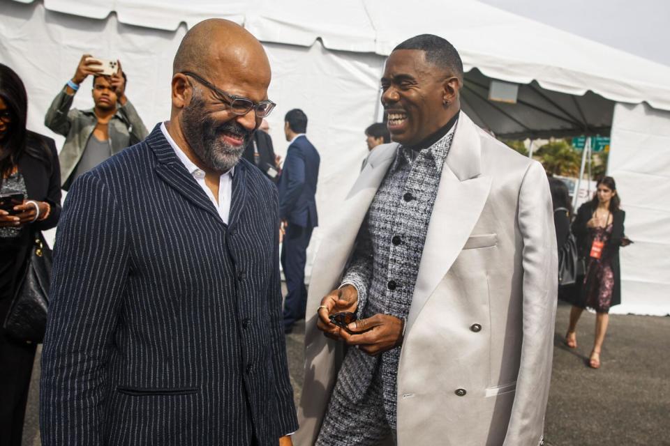 Two men laughing outside a large white tent