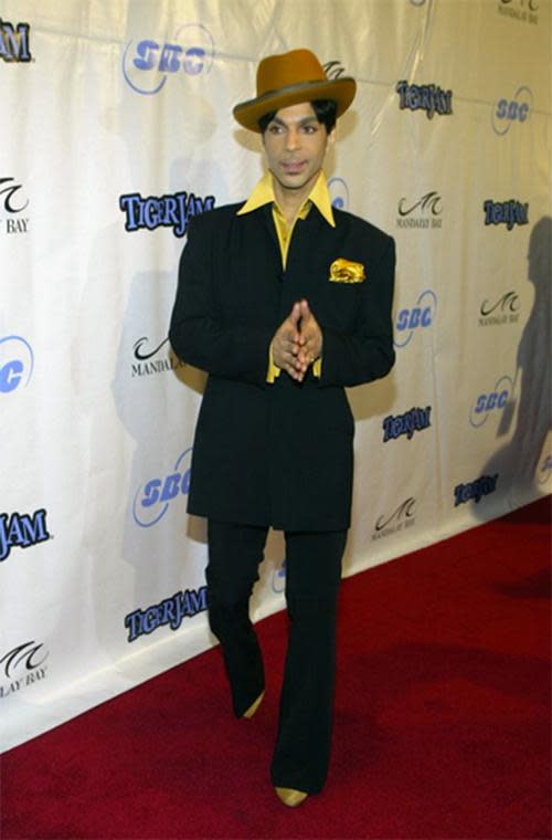 This is how you do dapper — Prince style. An oversize jacket, flared pants, a yellow shirt, shoes, and a pocket square with the hat tilted to the side for extra flair.