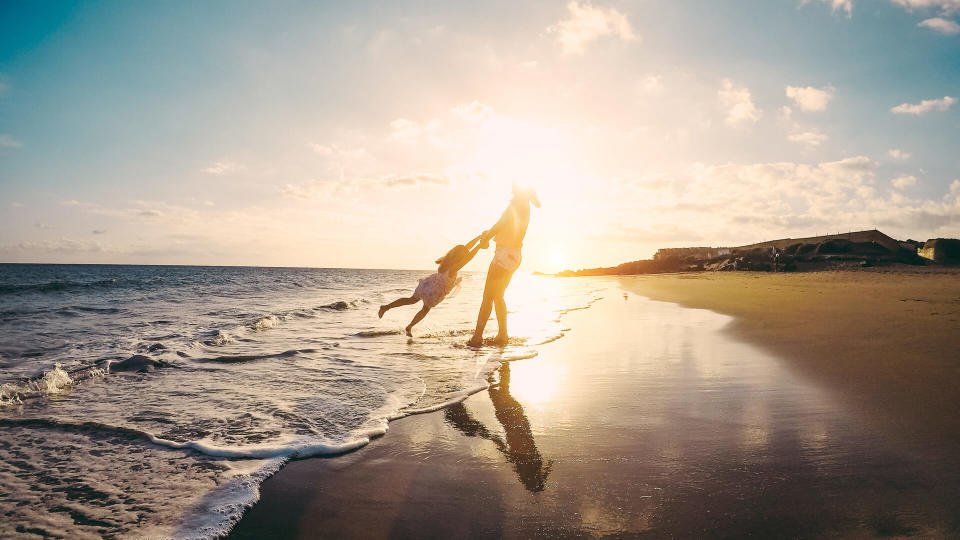 Mother and daughter having fun on tropical beach - Mum playing with her kid in holiday vacation next to the ocean - Family lifestyle and love concept - Focus on silhouettes.