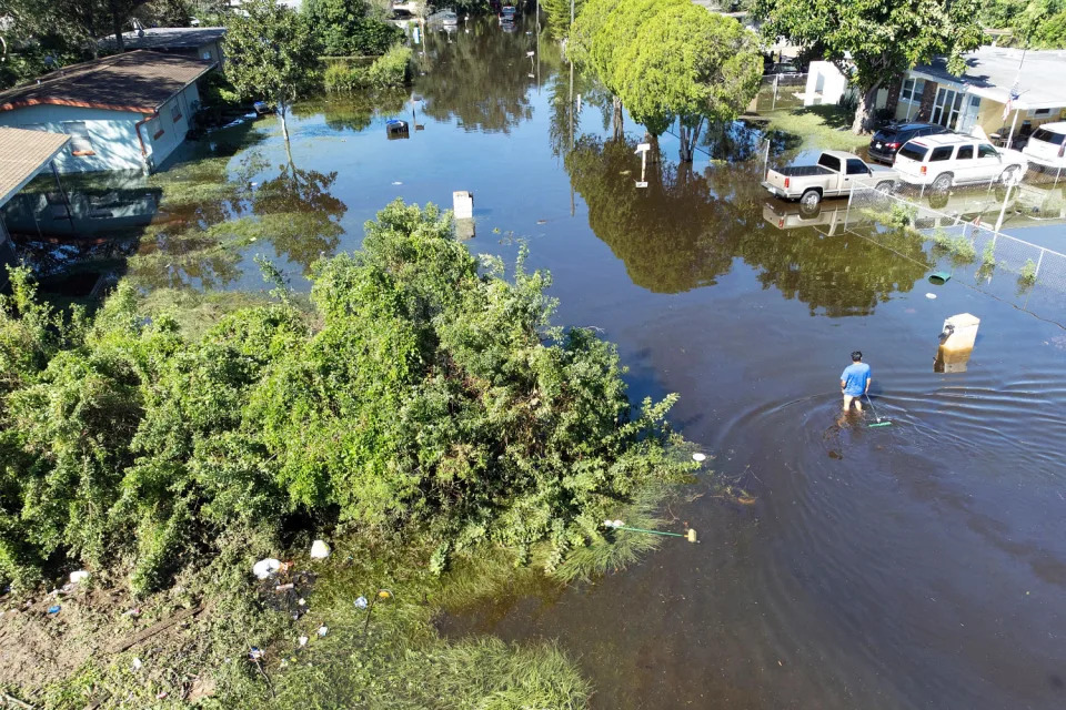 A aerial view of a man wading through a flooded street. (Bryan R. Smith / AFP via Getty Images)