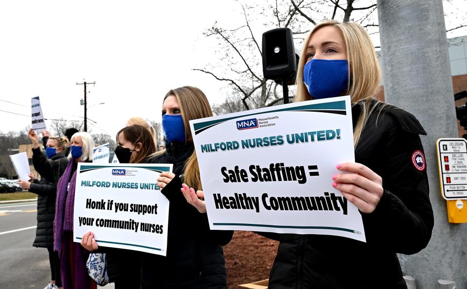 Jessica Rezendes, right, and Kelsey Capoccia, emergency room nurses at Milford Regional Medical Center, hold signs during a rally on the one-year anniversary of nurses at the hospital voting to unionize, Feb. 22, 2022.