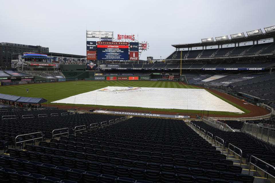 The tarp lies on the field as the scoreboard indicates that a baseball game between the Washington Nationals and the New York Mets was postponed due to inclement weather, Friday, Sept. 25, 2020, in Washington. (AP Photo/Nick Wass)