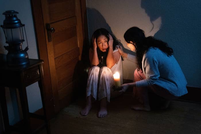 Sandra Oh crouches in the corner with her hands over her ears as another woman crouches down to console her