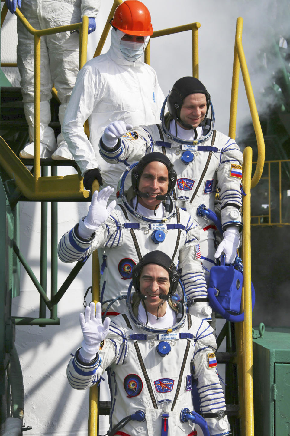 In this handout photo released by Roscosmos Space Agency Press Service U.S. astronaut Chris Cassidy, centre, Russian cosmonauts Anatoly Ivanishin, bottom, and Ivan Vagner, members of the main crew of the expedition to the International Space Station (ISS), wave as they board to the Soyuz MS-16 space ship prior to the launch at the Russian leased Baikonur cosmodrome, Kazakhstan, Thursday, April 9, 2020. (Roscosmos Space Agency Press Service via AP)