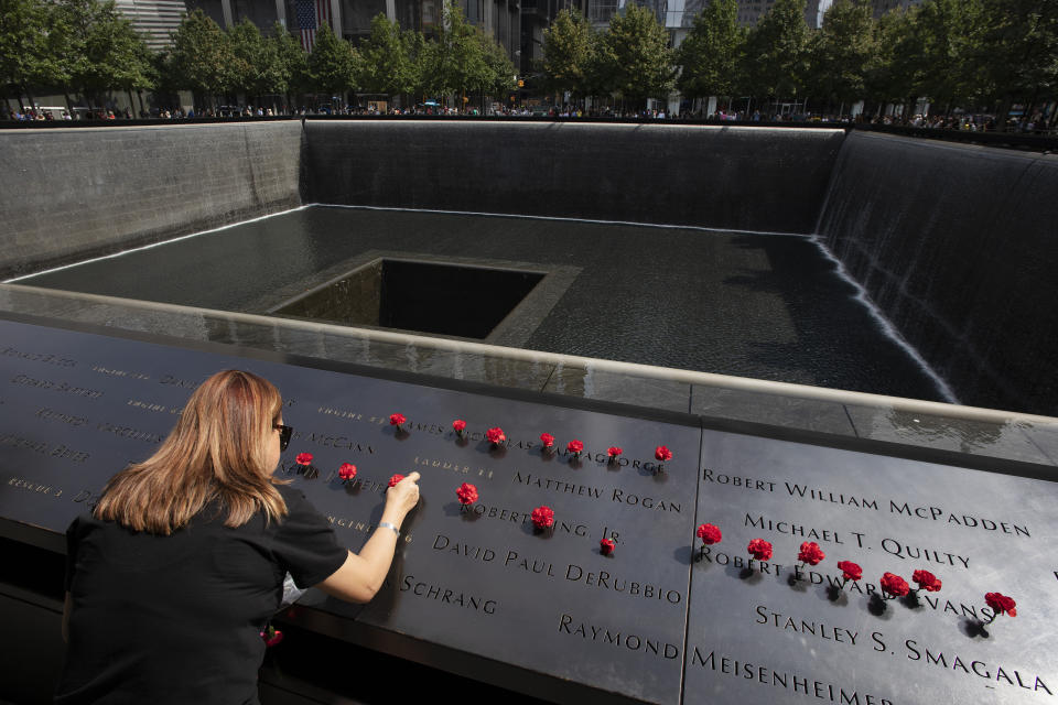 Norma Molina, of San Antonio, Texas, leaves flowers by the names of firefighters from Engine 33 at the September 11 Memorial, Monday, Sept. 9, 2019, in New York. Her boyfriend Robert Edward Evans, a member of Engine 33, was killed in the north tower of the World Trade Center on Sept. 11, 2001. (AP Photo/Mark Lennihan)