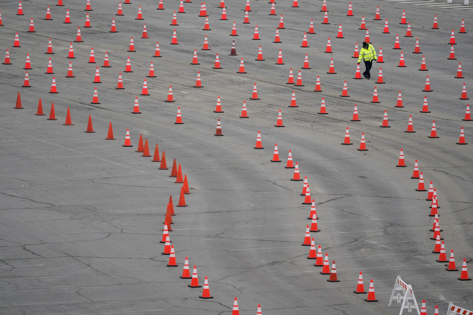 A worker arranges cones at a mostly-empty vaccination site at Dodger Stadium, Thursday, Feb. 11, 2021, in Los Angeles. A nationwide shortage of COVID-19 vaccines is hindering efforts to vaccinate residents of California and other states. Los Angeles temporarily shut down five mass vaccination sites, including Dodger Stadium, after running out of vaccine. (AP Photo/Marcio Jose Sanchez)