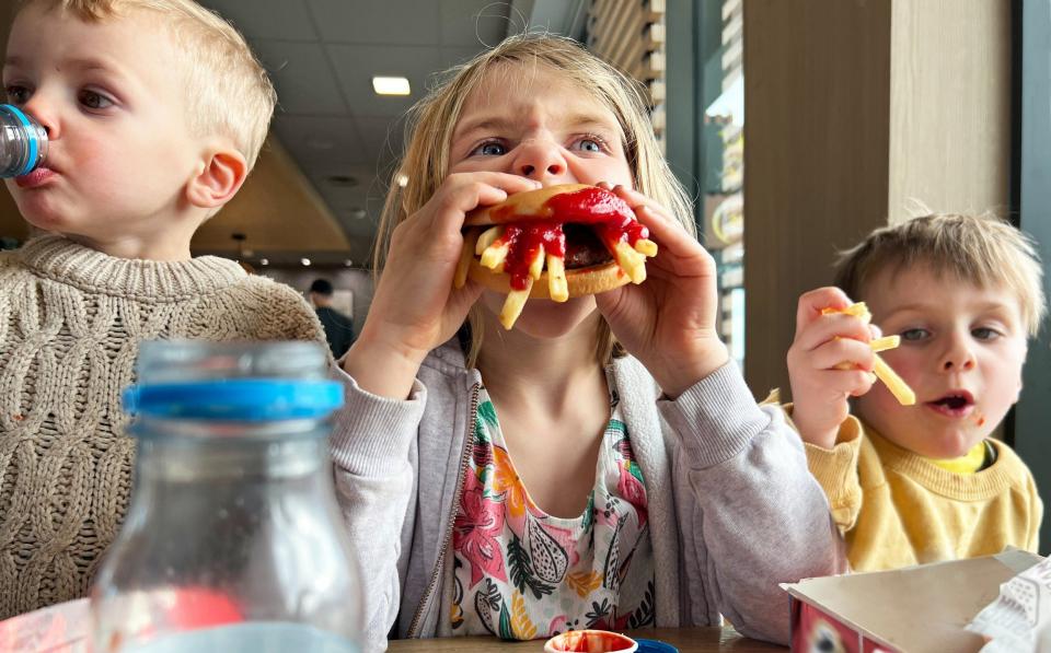 Young children eating burgers and chips