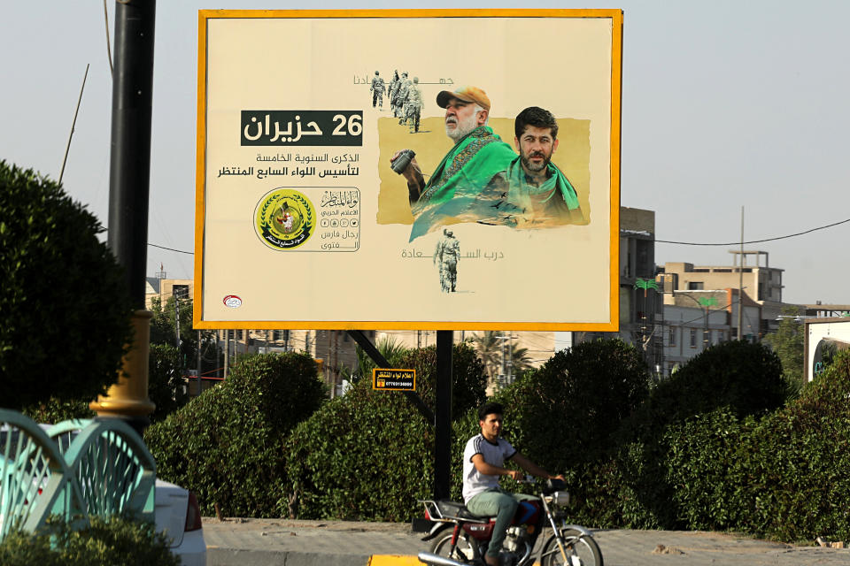 In this Tuesday, July 2, 2019 photo, motorists pass by a Popular Mobilization poster of volunteer militants who were killed in Iraq fighting Islamic State militants in Basra, Iraq. The Iraqi government's move to place Iranian-backed militias under the command of the armed forces is a political gamble by a prime minister increasingly caught in the middle of a dangerous rivalry between Iran and the U.S., the two main power brokers in Iraq. (AP Photo/Nabil al-Jurani)