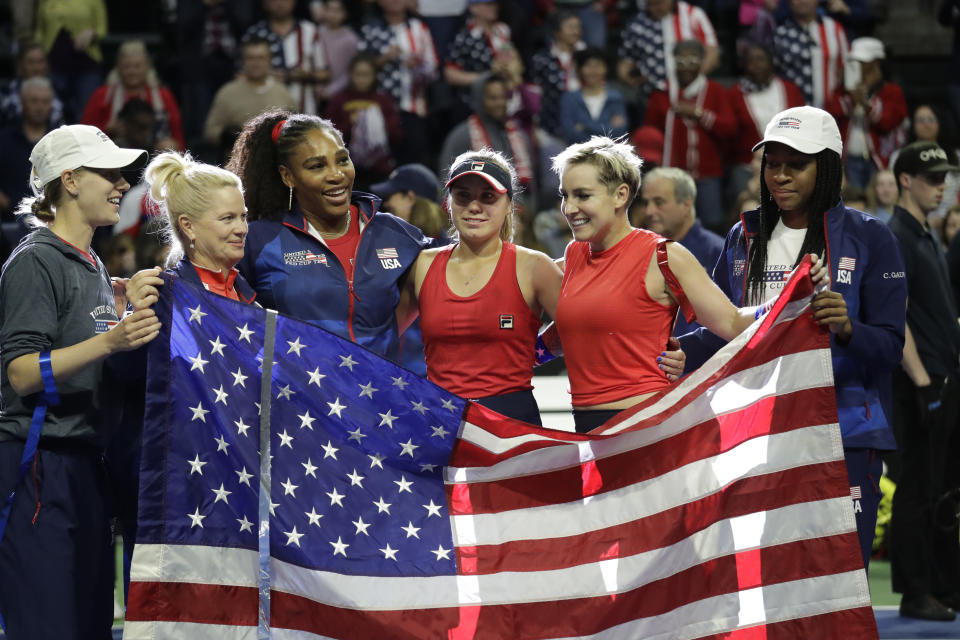 The United States Fed Cup team of Alison Riske, left, captain Kathy Rinaldi, Serena Williams, Sofia Kenin Bethanie Mattek-Sands and Coco Gauff pose with an American flag after beating Latvia in a Fed Cup qualifying tennis match Saturday, Feb. 8, 2020, in Everett, Wash. The U.S. won to advance in the tournament. (AP Photo/Elaine Thompson)