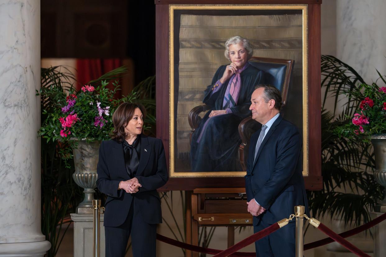 Vice President Kamala Harris, left, and second gentleman Doug Emhoff pay their respects as they walk past a portrait of retired Supreme Court Justice Sandra Day O'Connor as her casket lies in the Great Hall at the Supreme Court in Washington, Monday, Dec. 18, 2023.