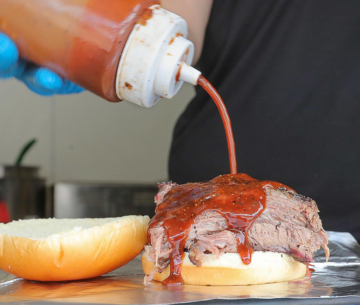 Joe Menendez, owner of Joe's Barbecue, slathers his famous sauce on a brisket sandwich at his temporarily location at the North Water Brewing Company in Kent.