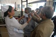 Doctors place a protective facemask on a patient coming with others to the outdoor patient department for an awareness event about the COVID-19 in Siliguri.