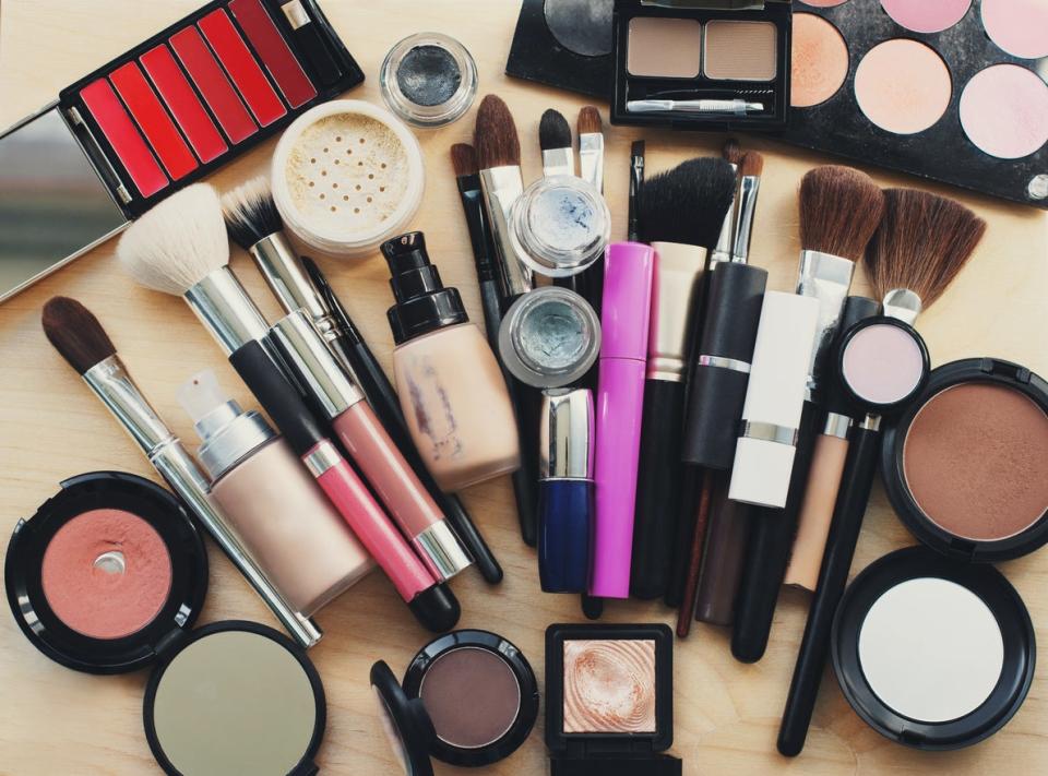 Makeup brushes, lipstick, eyeliner and mascara on counter with powder and other makeup items on display