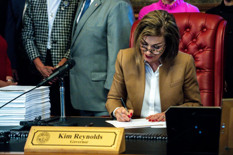 Gov. Kim Reynolds signs a bill to reorganize state government on Tuesday, April 4, 2023, at the Iowa State Capitol in Des Moines, Iowa.