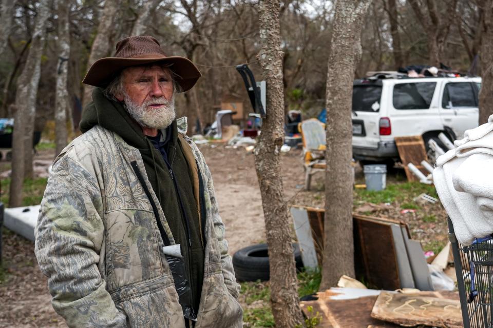 Resident Kent Romines wears multiple heavy layers in a camp in South Austin on Sunday, Jan. 14, 2024. Romines and other homeless Austin residents rely on blankets, clothing, tents, and fires to keep warm in cold weather.
