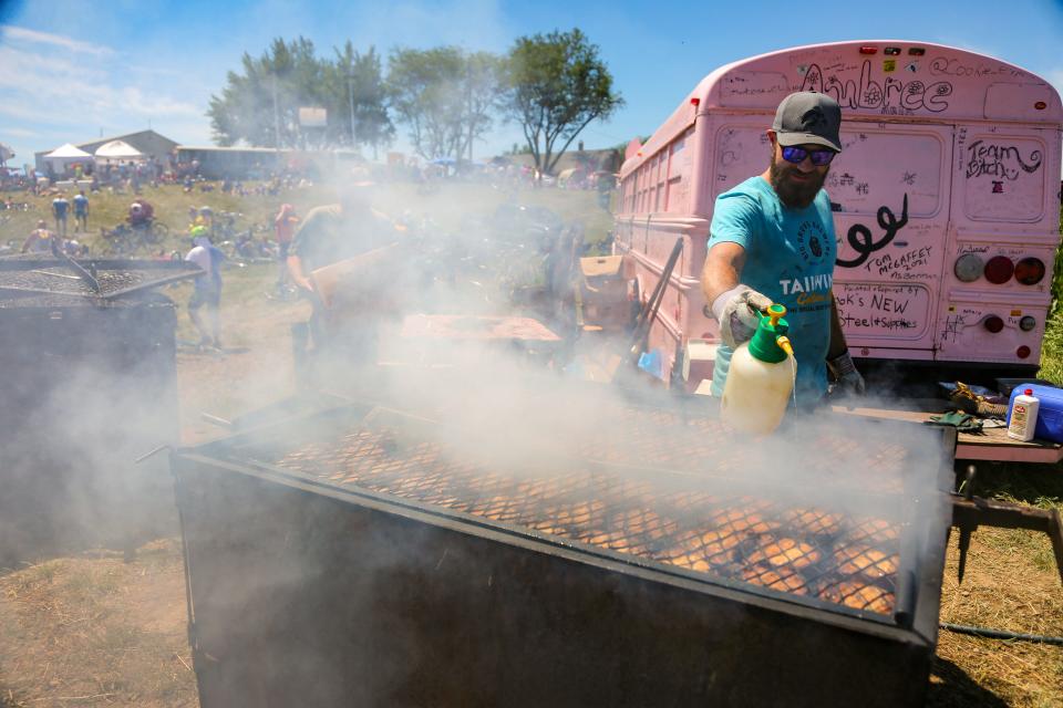 Ryan Shillinglaw sprays butter on pork chops at the Mr. Pork Chop bus outside of Anthon on the first day of RAGBRAI, Sunday, July 24, 2022.