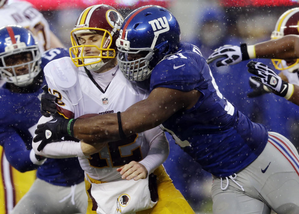 FILE - In this Dec. 29, 2013, file photo, New York Giants defensive end Justin Tuck, right, sacks Washington Redskins' Kirk Cousins (12) during the first half of an NFL football game in East Rutherford, N.J. Tuck signed with the Oakland Raiders. (AP Photo/Julio Cortez, File)