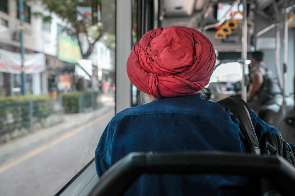 A man wearing a turban sitting on a bus.