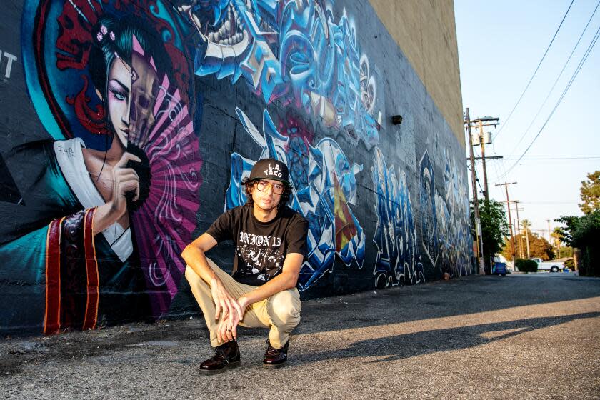 LOS ANGELES , CA - SEPTEMBER 30: Portrait of L.A. Taco editor, Javier Cabral in the alleyway behind the Figueroa Theatre on Wednesday, Sept. 30, 2020 in Los Angeles , CA. Among the artwork in the alley is an image of Mexican Revolutionary war hero Emiliano Zapata, depicted in skeleton form, by local artist MURAL ONE. (Mariah Tauger / Los Angeles Times)