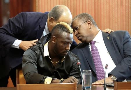 West Indies all-rounder Andre Russell (C front) sits at a desk during a meeting of an independent anti-doping tribunal at the Jamaica Conference Centre next to his lawyers Patrick Foster (L, rear, partially obscured) and Donovan Walker, in Kingston, Jamaica January 31, 2017. REUTERS/Gilbert Bellamy