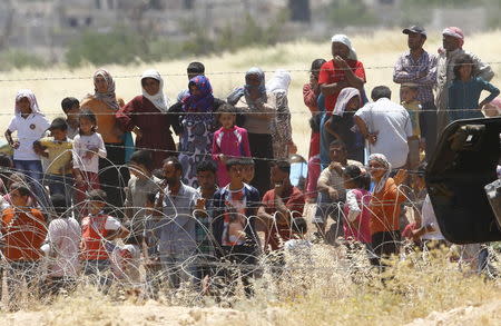 Syrian Kurds from Kobani wait behind the border fences to cross into Turkey as they are pictured from the Turkish border town of Suruc in Sanliurfa province, Turkey, June 26, 2015. REUTERS/Murad Sezer