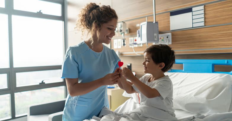 young beautiful nurse giving a lollipop to pediatrics hospitalized smiling child patient