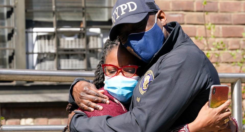 An NYPD police officer hugs a woman after the triple murder-suicide.