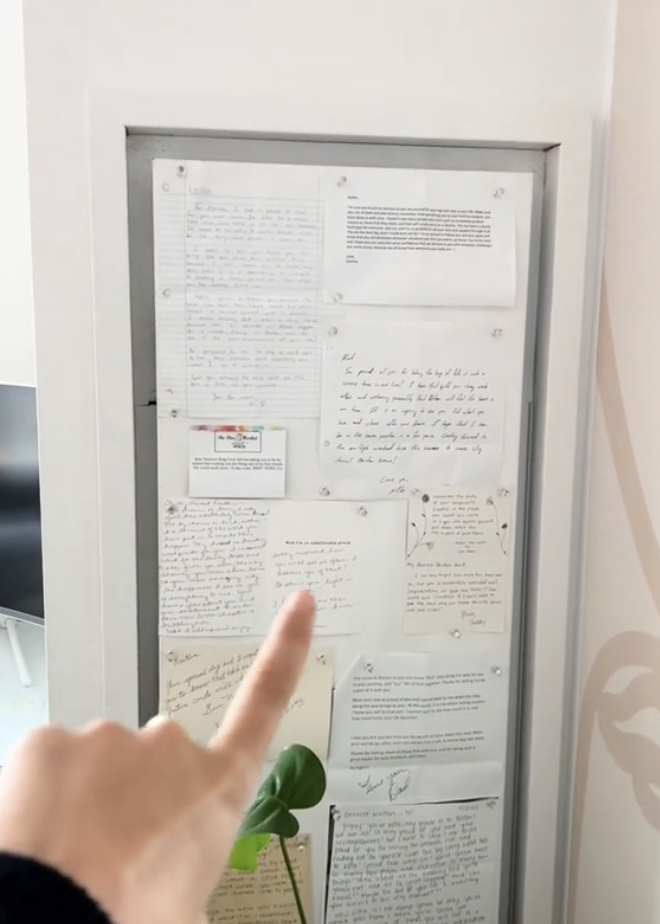 A door covered in handwritten notes with a person pointing to them