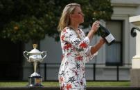 Germany's Angelique Kerber holds a bottle of champagne, with the women's singles trophy in the background, a day after winning her final match at the Australian Open tennis tournament, at the Government House in Melbourne, Australia, January 31, 2016. REUTERS/Jason Reed