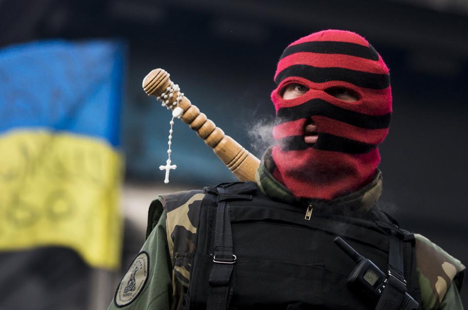 Anti-government protester looks across at riot police at a barricade in Kiev