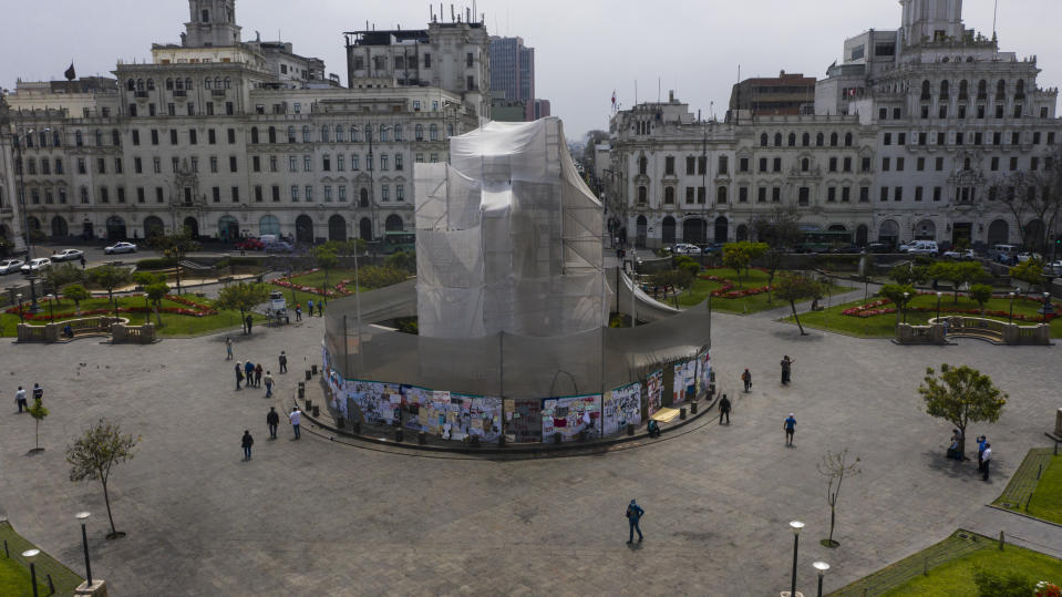 A monument to Argentine hero José de San Martín, who proclaimed the independence of Peru from the Spanish viceroyalty in 1821, is protected with cloth in the main square of Lima, Peru, Tuesday, Dec. 1, 2020, where for decades the largest political demonstrations have been concentrated. The wooden plates that cover the pedestal of the statue have become blackboards where some protesters have written anti-government messages. (AP Photo/Rodrigo Abd)