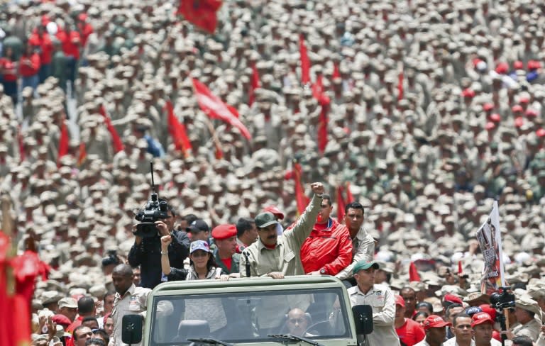 Venezuelan President Nicolas Maduro (C) saluting next to his wife Cilia Flores as they arrive for the celebrations for the seventh anniversary of the Bolivarian Militia in Caracas on April 17, 2017